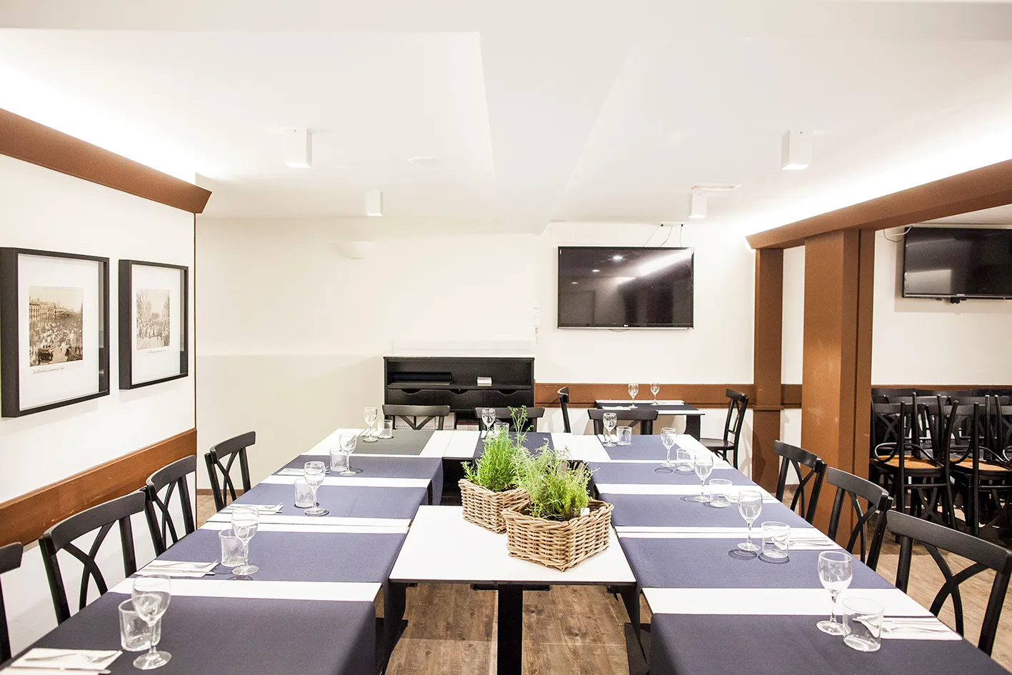 Tables pushed together and set for a group dinner at Santa Anna, with glasses and baskets of rosemary in the middle.